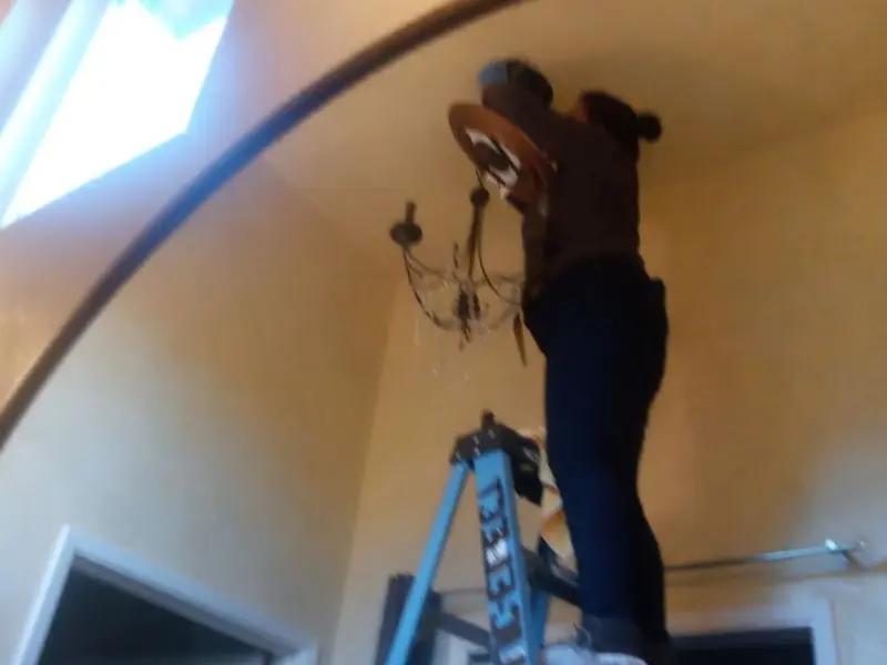 Electrician installing a chandelier in a Marion residence